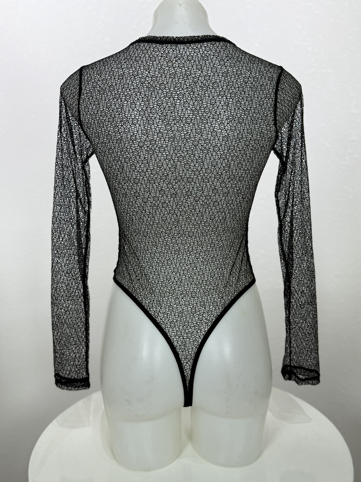 Back view of the Vervain black mesh bodysuit on a mannequin.